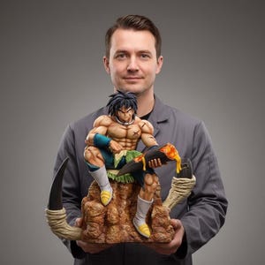 May include: A detailed figurine of a muscular anime character with green and blue accents, seated on a brown rock formation. The figure is holding a dark object with orange liquid. The figurine is held by a person in a gray jacket.