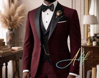 May include: A burgundy three-piece suit with a black lapel and bow tie. The suit includes a vest, jacket, and trousers. A gold chain and a floral boutonniere add detail. The man is wearing a white dress shirt.