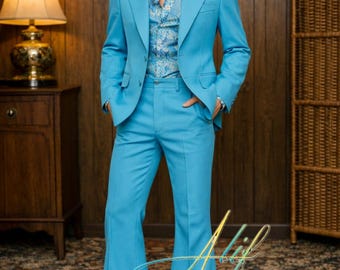 May include: A light blue suit with a flared leg design. The suit includes a two-button jacket and matching pants. The shirt underneath has a blue and white paisley pattern. The person is wearing white shoes. The background is a wood-paneled wall.