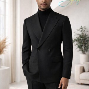 May include: A black double-breasted suit with a black turtleneck. The suit has a classic design with a notched lapel and two buttons. The person is standing in a well-lit room with a neutral background.