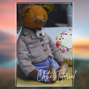 Op de afbeelding: Een bruine teddybeer met een geruit jasje, een blauwe broek en een vlinderdas. Naast de beer ligt een speldenkussen met bloemenborduurwerk en spelden. De tekst "Clothes Tutorial" staat in cursief onderaan.