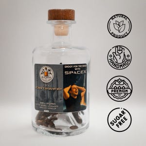 May include: A clear glass bottle with a wooden stopper, filled with coffee beans. The label reads "BLENDY TRY Cape Canaveral" and "SHOOT FOR THE STARS WITH SPACEX." Additional labels indicate the product is natural, handmade, premium, and sugar-free.