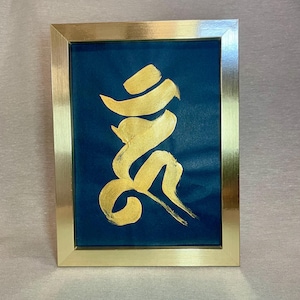 May include: Gold calligraphy art on a dark blue background, framed in a gold-tone rectangular frame. The artwork features flowing, abstract shapes. The frame has a simple, elegant design, suitable for home decor.