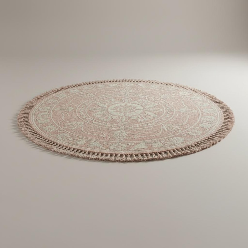 May include: A round, pink rug with a cream-colored floral pattern in the center. The rug has a fringe border and is approximately 60 inches in diameter. The rug is suitable for a living room or bedroom.