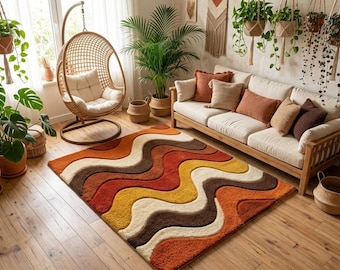 May include: A rectangular area rug featuring a repeating wavy pattern in shades of cream, yellow, orange, and dark brown. The rug has a thick, textured pile and is positioned on a light-colored wooden floor in a room filled with various potted plants.