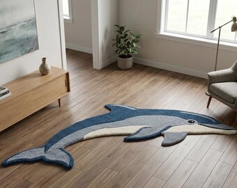 May include: A dolphin-shaped rug in shades of blue, gray, and cream rests on a hardwood floor. The rug features a detailed design with a smiling face and fins. The room includes a wooden cabinet, a chair, and a painting.