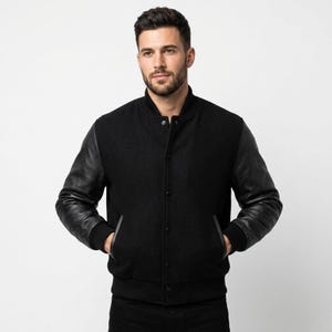 May include: A black varsity jacket with leather sleeves. The jacket has a button-up front, two front pockets, and ribbed cuffs and hem. The jacket is worn by a person.