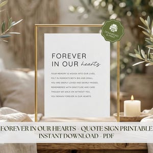 May include: A framed print with the words "FOREVER IN OUR hearts" in elegant script. The text below reads "Your memory is woven into our lives." A candle and greenery are in the background.