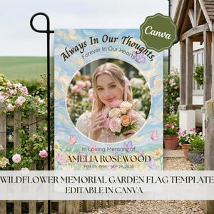 Può includere: Una bandiera da giardino con un ritratto di una donna che tiene dei fiori, circondata da un disegno dipinto di blu e bianco. Il testo recita "Always In Our Thoughts, Forever in Our Hearts" e "In Loving Memory of AMELIA ROSEWOOD".