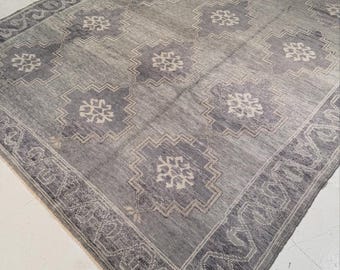 May include: A rectangular area rug featuring a gray and off-white color palette. The rug displays a repeating pattern of geometric, star-like medallions centered within larger octagonal shapes, all framed by a wide, intricate border.