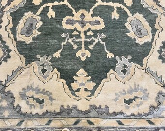 Peut inclure: Un grand tapis présentant un fond vert forêt profond avec des motifs symétriques complexes en crème, bleu clair et gris anthracite. Le design comprend des motifs floraux et géométriques stylisés disposés de manière répétitive.
