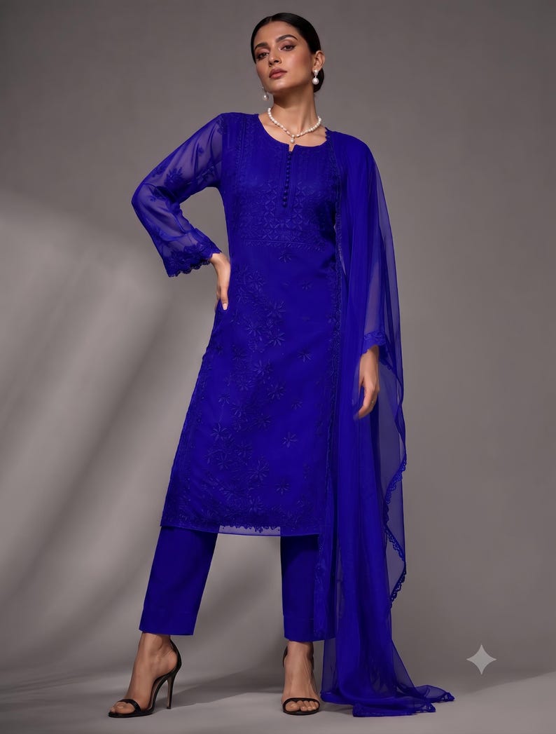 Puede incluir: Un vibrante conjunto de tres piezas en azul real que consta de una t&uacute;nica de manga larga con intrincados bordados tonales, un pantal&oacute;n de corte recto a juego y una dupatta ligera y transparente con un delicado borde de encaje festoneado.