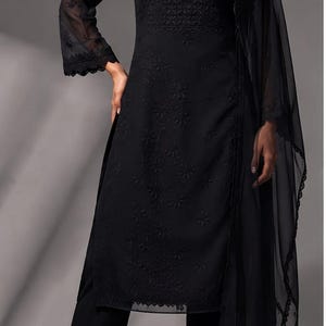 Puede incluir: Un conjunto negro de tres piezas que consta de una t&uacute;nica de manga larga con intrincados bordados tonales, un pantal&oacute;n recto a juego y un dupatta ligero y transparente con un delicado borde de encaje festoneado en los extremos.