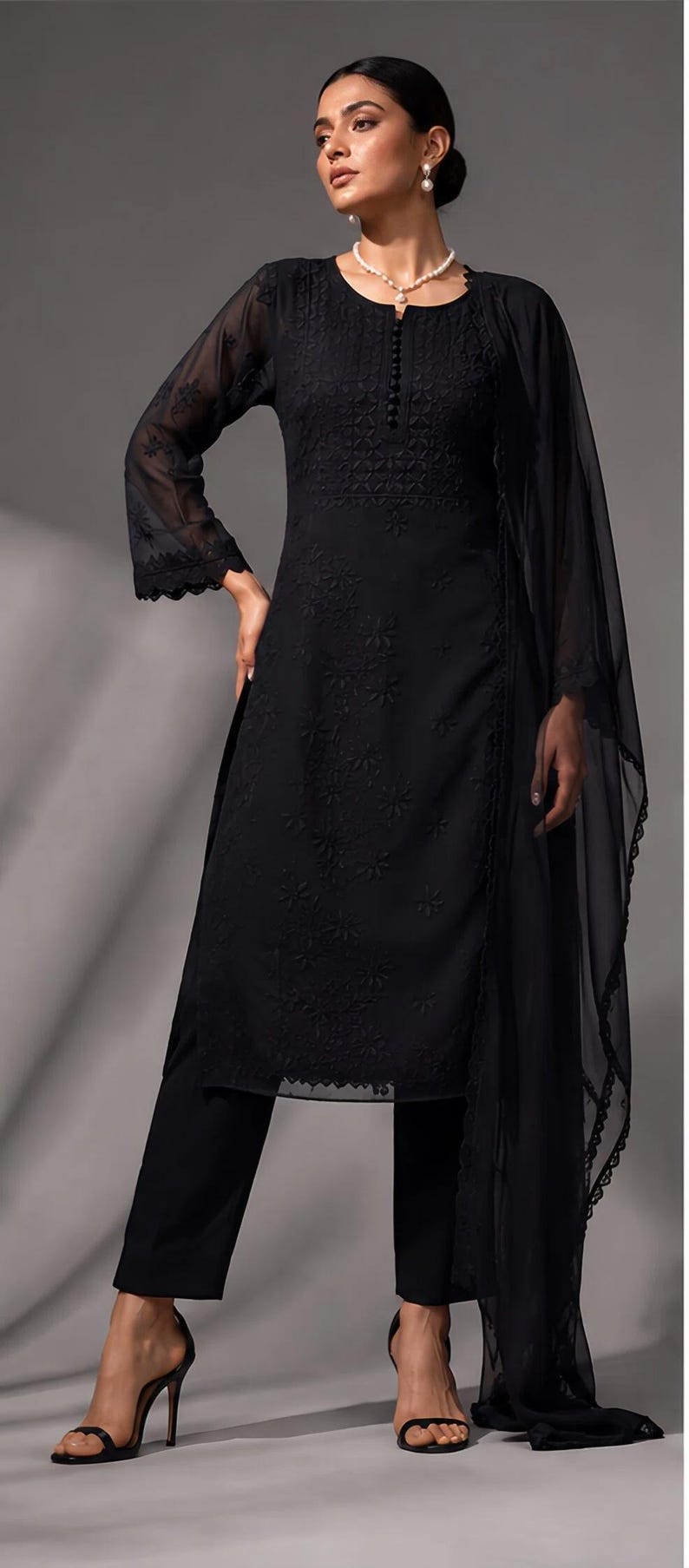 Puede incluir: Un conjunto negro de tres piezas que consta de una t&uacute;nica de manga larga con intrincados bordados tonales, un pantal&oacute;n recto a juego y un dupatta ligero y transparente con un delicado borde de encaje festoneado en los extremos.