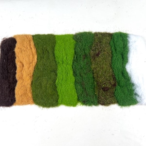 Może przedstawiać: Kolekcja ośmiu próbek sztucznej trawy o różnej fakturze w różnych kolorach. Kolory wahają się od ciemnobrązowego do jasnobrązowego, różnych odcieni zieleni i bieli. Próbki są ułożone obok siebie na białej powierzchni.