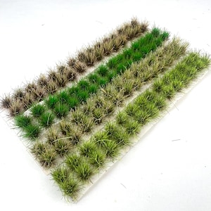 Op de afbeelding: Miniatuur grasplukjes in verschillende groen- en bruintinten, gerangschikt in rijen op een witte ondergrond. Modelbouwaccessoires voor het creëren van realistische miniatuurscènes.