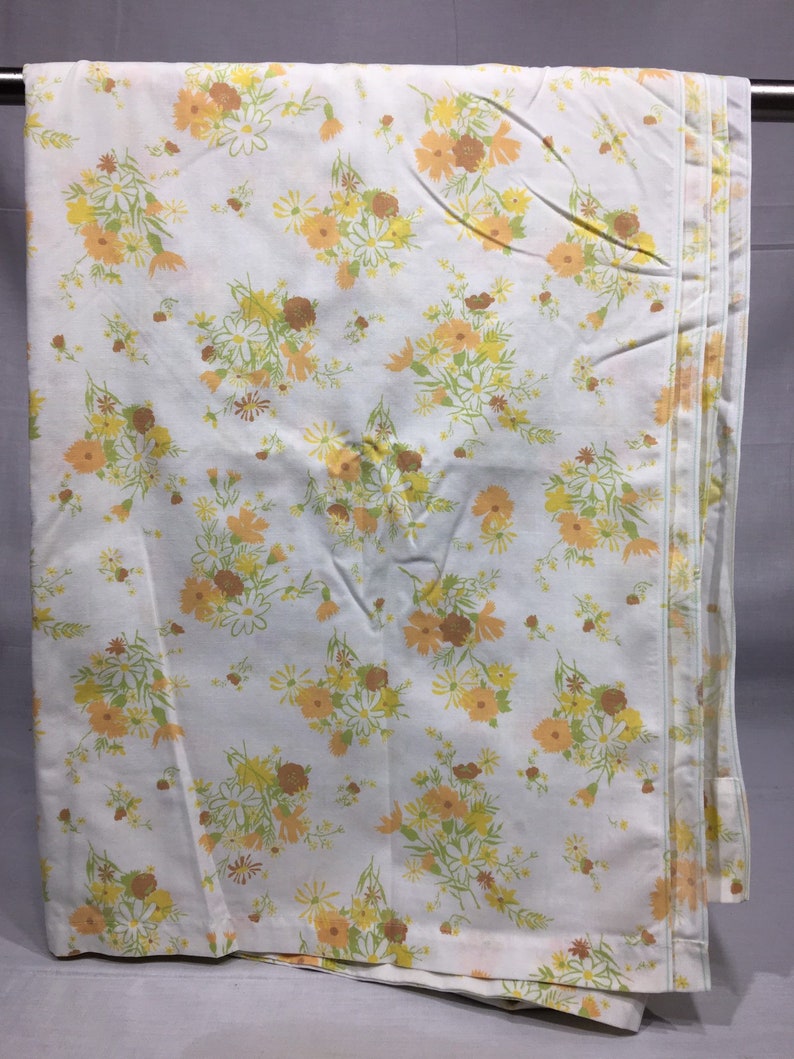 Pu&ograve; includere: Un lenzuolo bianco con un motivo floreale in tonalit&agrave; di giallo, arancione e verde. I fiori sono piccoli e sparsi su tutto il lenzuolo.