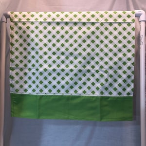 May include: A green and white checkered valance with a solid green bottom border. The valance is hung on a white pipe.