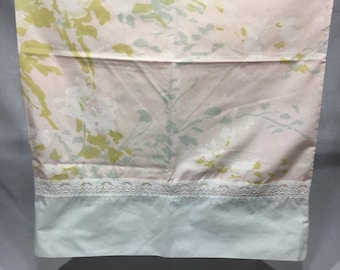 May include: A pink and white floral patterned bed sheet with a white lace trim and a light blue solid color bottom border.
