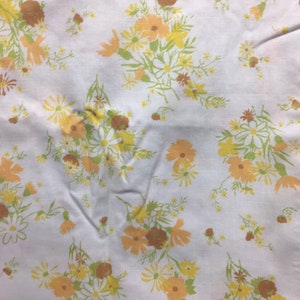Pu&ograve; includere: Tessuto bianco con un motivo floreale con fiori gialli, arancioni e marroni. I fiori sono disposti a grappoli e sono sparsi sul tessuto.