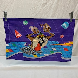 May include: A purple pillowcase with a cartoon Tasmanian Devil character in a yellow hat. The character is surrounded by a blue and white checkered pattern with colorful squares and the words "50 pts", "25 pts", and "15 pts".