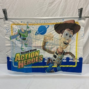 May include: Toy Story Action Heroes pillowcase featuring Buzz Lightyear and Woody.  The blue and yellow design includes the text 'Buzz and Woody Action Heroes' against a white background with space-themed graphics.  The pillowcase shows Buzz in flight and Woody in action poses.