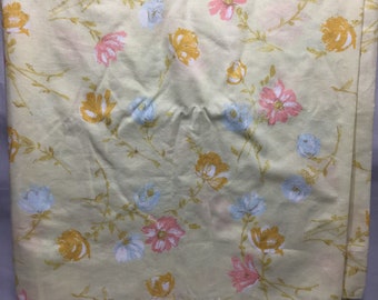 Pode incluir: Um lençol de cama amarelo com padrão floral em rosa, azul e amarelo.