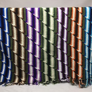 Vintage afghan handmade in stripes of purple, orange, gree, white, blue, black, and brown in a striped pattern, handmade, retro baby blanket
