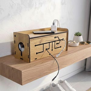 May include: A wooden charging station with a circuit board design, a phone, and a charger on top. The station sits on a floating wooden shelf with white sneakers below. A small succulent and sunglasses are also on the shelf.