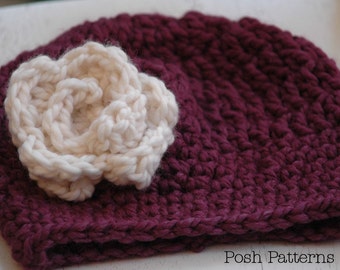Puede incluir: Un gorro de punto burdeos con una gran flor de ganchillo blanca en la parte superior.