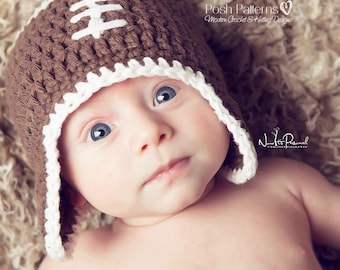 May include: A baby wearing a brown and white crocheted football helmet hat. The hat has a white brim and a brown crocheted football design.