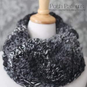 May include: A black and white knit cowl neck scarf with a textured pattern. The scarf is displayed on a white mannequin with a wooden head.