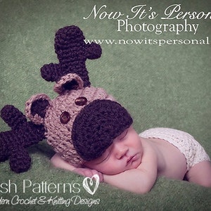 May include: A baby wearing a crocheted reindeer hat with brown antlers and a white crocheted diaper. The baby is sleeping on a green blanket. The image includes the text "Now It's Personal Photography" and "www.nowitspersonal.net".