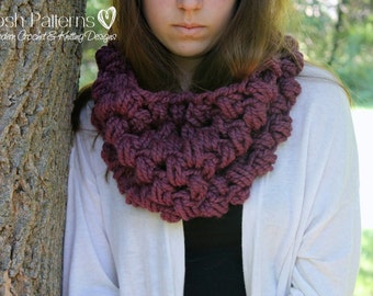 Puede incluir: Primer plano de una mujer con una bufanda de cuello alto de punto de color morado oscuro. La bufanda está hecha con un hilo grueso y tiene un diseño texturizado y tejido. La mujer lleva una chaqueta blanca y tiene el pelo largo y castaño.