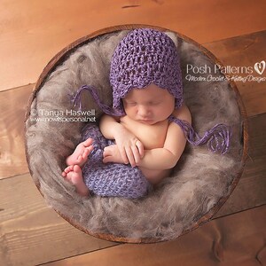 May include: A sleeping baby wearing a purple crocheted hat and matching pants in a wooden bowl filled with brown faux fur.