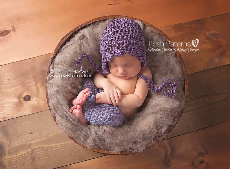May include: A sleeping baby wearing a purple crocheted hat and matching pants in a wooden bowl filled with brown faux fur.