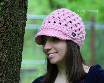Könnte beinhalten: Eine rosa gehäkelte Mütze mit Knopfdetail. Die Mütze hat einen breiten Rand und ein Spitzenmuster.