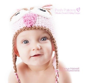 Pode incluir: Um bebê usando um chapéu de crochê de coruja rosa e marrom. O chapéu tem um nariz rosa e olhos brancos. O bebê está olhando para a câmera e sorrindo.