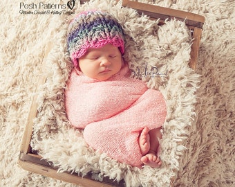 May include: A newborn baby wearing a pink and purple crocheted hat, swaddled in a pink blanket, and sleeping in a wooden box lined with white faux fur.