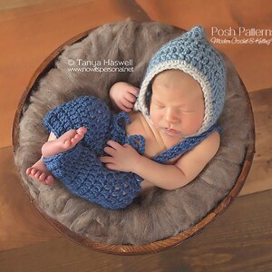 May include: A newborn baby wearing a blue crocheted hat and matching pants, sleeping in a wooden bowl lined with brown faux fur. The hat has a white trim. The text "Posh Patterns" is visible in the top right corner of the image.