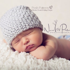 Puede incluir: Un beb&eacute; reci&eacute;n nacido con un gorro de ganchillo gris, durmiendo sobre una superficie blanca y esponjosa. El beb&eacute; lleva un pa&ntilde;al azul y marr&oacute;n. La imagen incluye el texto "Now It's Personal Photography" y "Posh Patterns Modern Crochet & Knitting Designs".