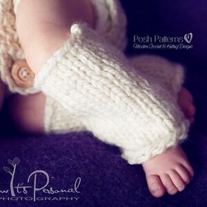 May include: Close-up of a baby's foot wearing a white knitted leg warmer. The leg warmer has a ribbed texture and is folded over at the top. The baby's foot is resting on a purple surface.