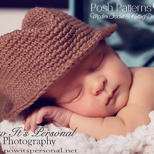 May include: A brown crocheted hat with a brim, worn by a sleeping baby. The hat is made with a simple stitch pattern and has a soft, textured look.