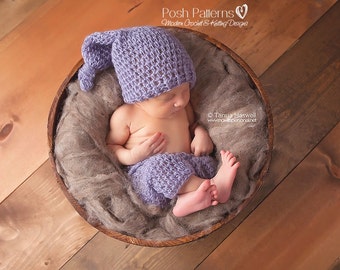 Puede incluir: Un bebé recién nacido con un gorro y pantalones de punto de color morado, durmiendo en un cuenco de madera lleno de piel sintética marrón.