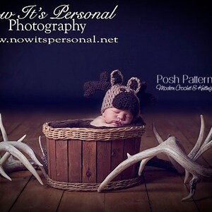 May include: A newborn baby wearing a brown crocheted moose hat is sleeping in a wooden basket. Two white antlers are on either side of the basket. The image is captioned "Now It's Personal Photography www.nowitspersonal.net" and "Posh Patterns Modern Crochet & Knitting Designs".