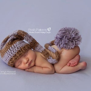 Może przedstawiać: Noworodek w brązowo-fioletowym, dzianym czapce z długim ogonem i pasującą fioletową pomponową kitką. Dziecko śpi na jasnofioletowym tle.