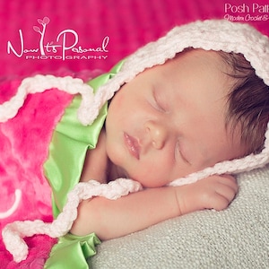 May include: A newborn baby wearing a white crocheted bonnet, sleeping on a pink and green blanket. The blanket has the text "Now It's Personal Photography" on it.