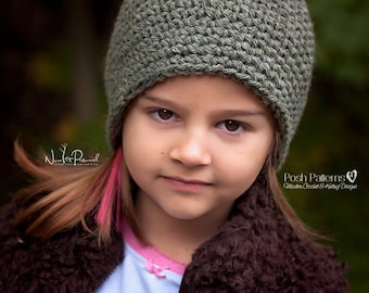May include: A young person wearing a green crocheted beanie hat and a brown fuzzy jacket. The person has long brown hair with a pink streak.