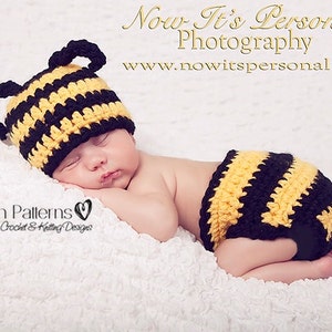 May include: A sleeping baby wearing a yellow and black crocheted bee hat and matching diaper cover. The baby is lying on a white fluffy blanket. The image includes the text "Now It's Personal Photography" and "www.nowitspersonal.net".