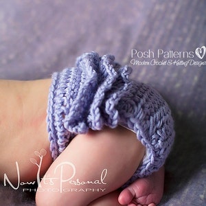 Puede incluir: Primer plano de un bebé con una cubierta de pañal de ganchillo morado con un borde rizado. El bebé está acostado sobre una superficie texturizada morada.